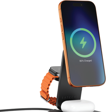 Photo of the Satechi 3-in-1 Foldable Wireless Charging Stand with Qi2 25W, showing an iPhone charging on the magnetic Qi2 pad, an orange Apple Watch on the foldable side arm, and AirPods resting on the base pad.